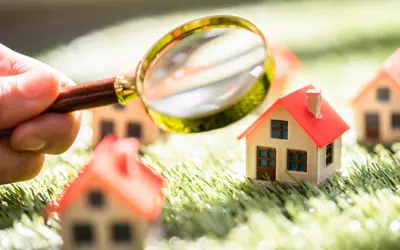 mini block houses being looked at by a hand holding a magnifying glass